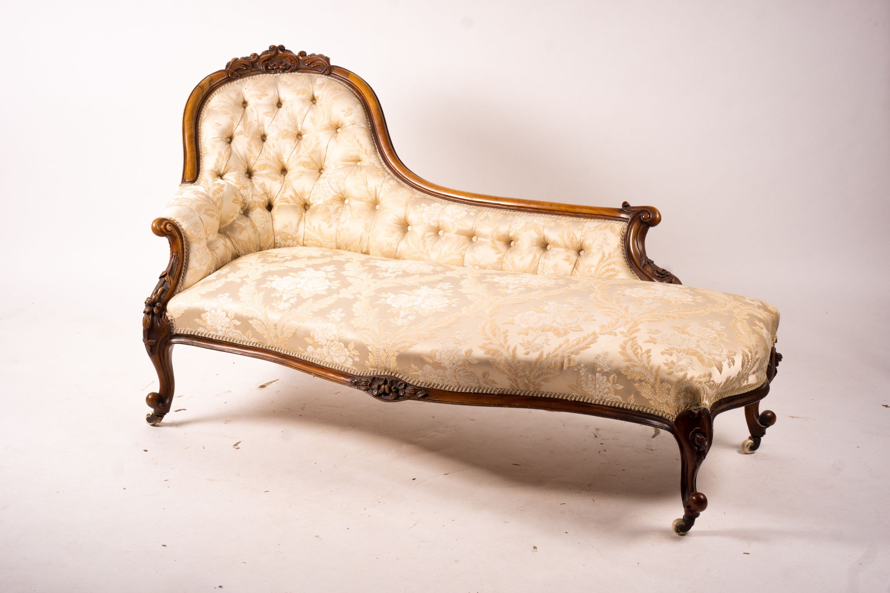 A late Victorian carved walnut three piece salon suite, comprising chaise longue, open armchair and nursing chair